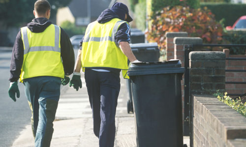 Bin crew wheeling wheelie bin on a street