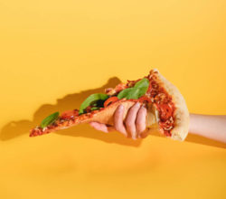 someone holding a slice of pizza