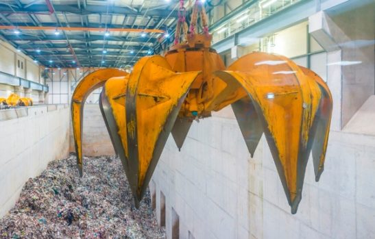 A grabber hanging over a pit of general waste