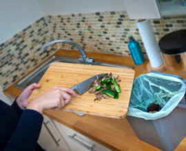 A person scrapping food waste into a kitchen caddy