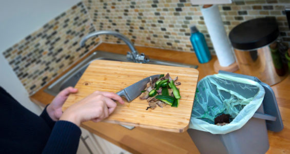 A person scrapping food waste into a kitchen caddy
