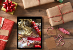 Christmas presents and tablet showing wrapping paper on screen