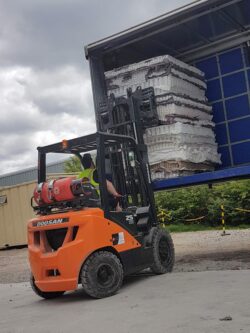 a forklift lifting a pile of foam removed from matresses
