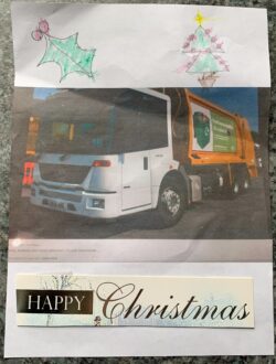 Picture of a bin wagon with holly and a Christmas tree and Happy Christmas below it.