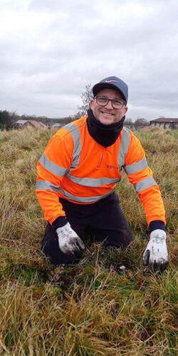 Suez employee in high vis in field checking soil