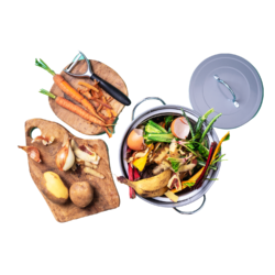 Two chopping boards with vegetables peelings and a bin beside it with inedible scraps of vegetable and fruit skin