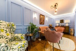Different angle of staged living room at the renew hub. includes a suede muted orange sofa and matching single chairs, a rug and lemon tree print armchair.
