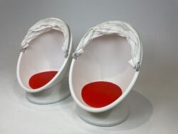 Image of two white retro egg chairs with red seat