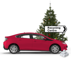 Image of red car, a road sign arrow reading recycling centre, and behind the sign a Christmas tree.
