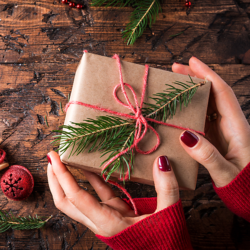 Image of women's hands holding a Christmas present wrapped in paper wrapping