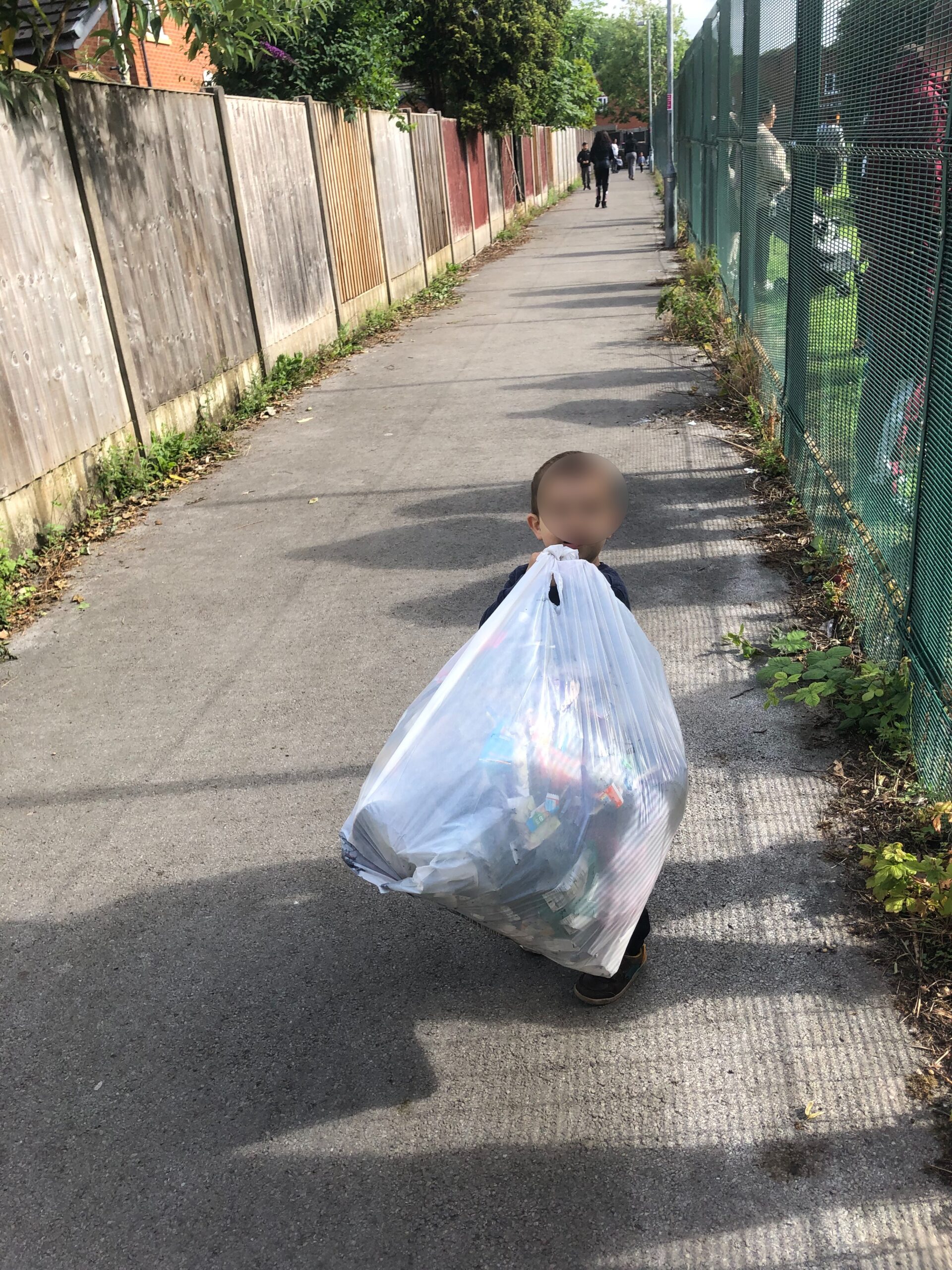 Young boy litter picking near a school