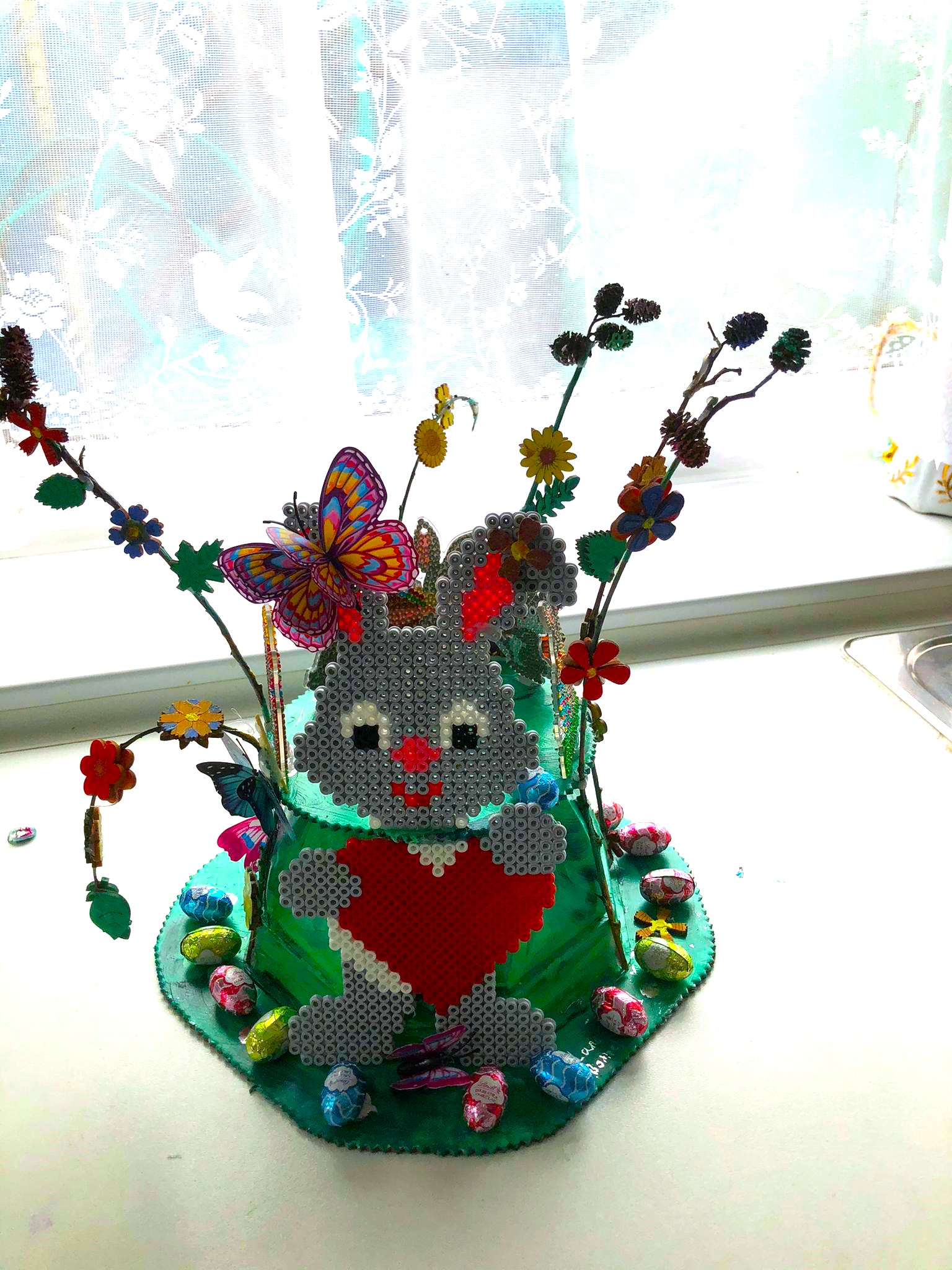 Easter bonnet, made from cake box and twigs and some older toys that we made earlier with Hama beads.