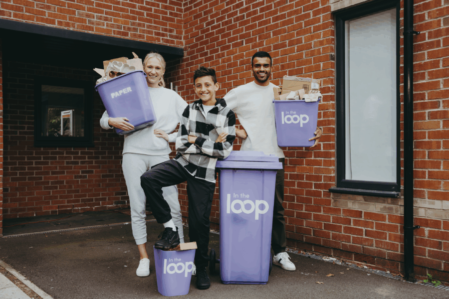 a family stood with holding bins which have recycling in 3 bins say in the loop one says paper