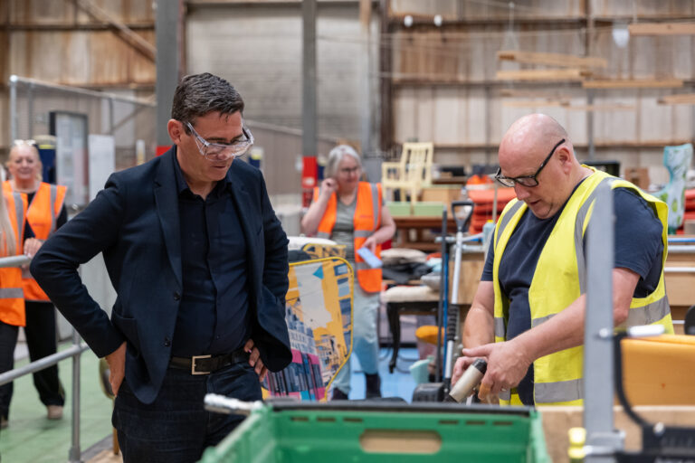 an upholsterer, showing Andy Burnham how to reupholster a chair