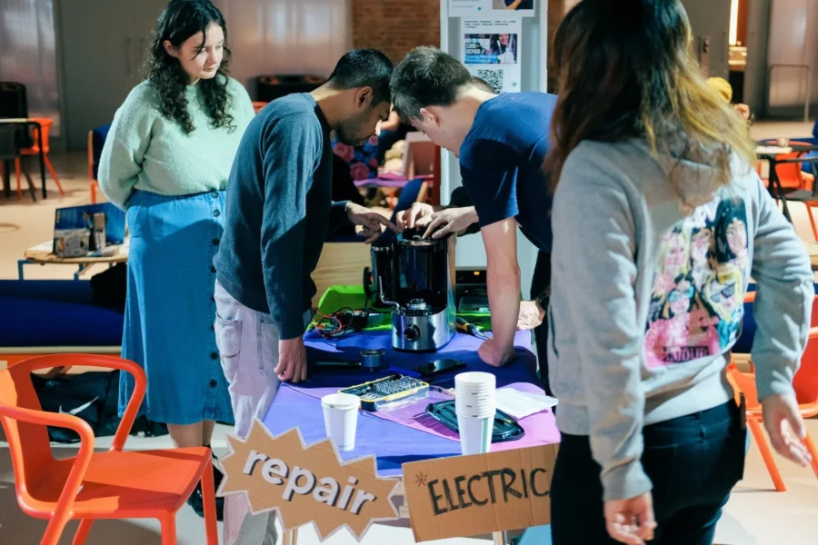 people at a repair cafe fixing a coffee machine