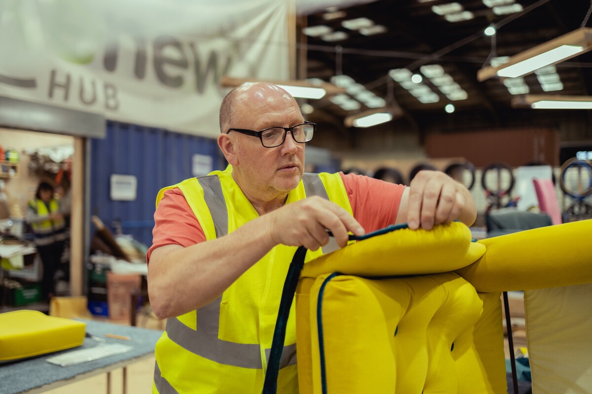 person re-upholstering a yellow chair